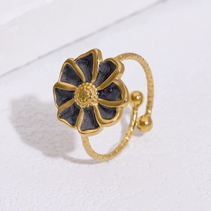 Close-up of gold stainless steel flower ring with black petals and sparkly resin inlay