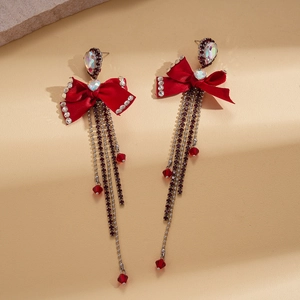 Macro detail of red bowknot earrings with crystal rhinestones and long bead tassels