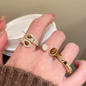 Three-piece gold-toned ring set featuring tiger eye stones and cubic zirconia on a model
