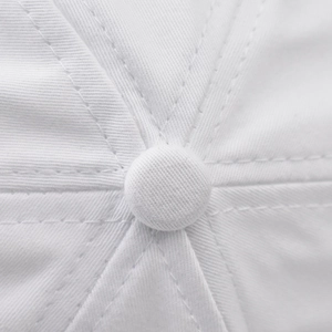 Macro detail of white cotton baseball cap crown with stitched panels and top button