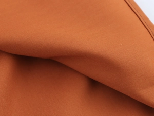 Gros plan sur le tissu en popeline orange montrant la texture fine et la couture