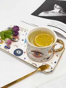 Detail of Evil Eye ceramic coffee set with gold handle cup and tray on white background