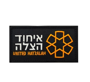 Close-up of United Hatzalah tactical patch with orange embroidery on black nylon fabric