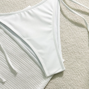 Detail of white bikini bottoms with side ties on a soft textured neutral background