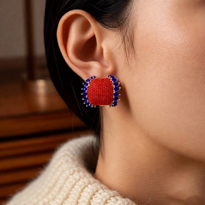 Close-up of vintage square stud earrings with red and blue crystals on a model