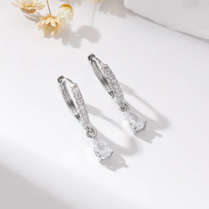 Detailed view of silver hoop earrings with teardrop zircon pendants and micro-pave crystals