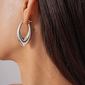 Macro close-up of a minimalist silver hollow teardrop earring worn on a model's ear