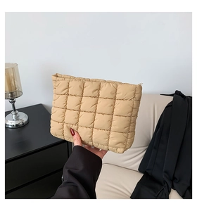 Macro detail of khaki pleated clutch bag with quilted pattern in a modern home setting