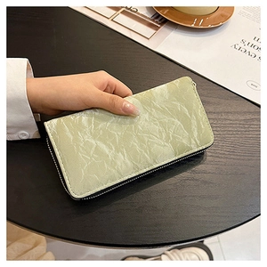 Detail of light green velvet wallet showing zip closure and unique pleated texture