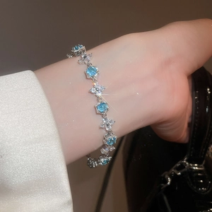 Close-up of a silver flower bracelet with sky blue zircons worn on a model's wrist