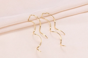 Macro shot of elegant golden spiral S925 silver thread earrings on beige fabric background