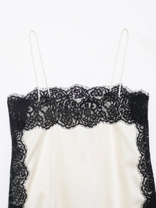 Detail of cream silk camisole top featuring delicate black lace trim and thin straps