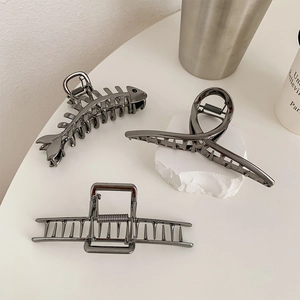 Close-up of three gunmetal hair claws in fishbone, twisted, and hollow styles