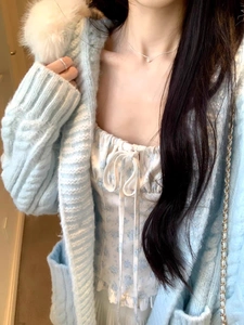 Dettaglio cardigan in maglia celeste con collo in pelliccia su top floreale bianco