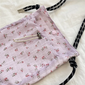 Macro detail of lavender floral seersucker canvas bag with woven drawstring and metal aglets