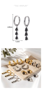 Detail view of drop earrings with black stones in gold and silver finish on white silk