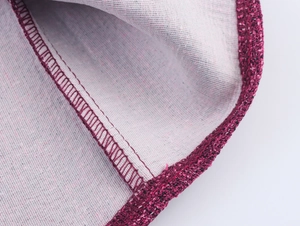 Detail view of purple tweed fabric featuring precision overlock stitching and woven texture