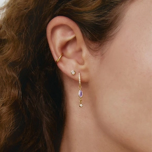 Elegant gold drop earrings with purple marquise zircon stones worn on model