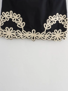 Détail du tissu noir élégant avec broderie beige complexe et bordure en dentelle ajourée