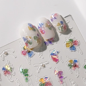 3D clover nail stickers with iridescent floral patterns and pearl accents on white nails