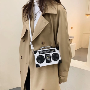 Vintage radio shaped crossbody bag in black and white worn with a khaki trench coat
