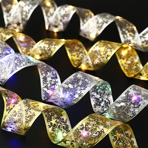 Detail of LED Christmas ribbon lights with gold mesh and warm glowing stars and notes