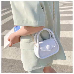 Outdoor shot of a white mini jelly bag with gold chain and large round buckle detail