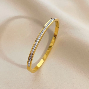 Minimalist gold-plated bangle with full row of white cubic zirconia stones on satin