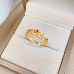 Close-up of golden bow ring with a pink center stone and white diamond accents in a jewelry box