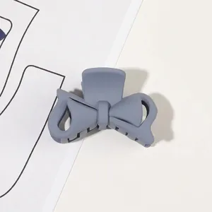 Close-up of matte grey-blue bow hair claw clip showing frosted texture and structure