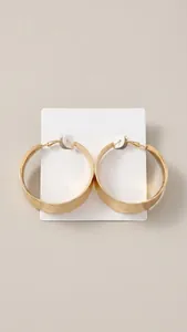 Detailed view of large golden C-shaped hoop earrings with a brushed metallic finish