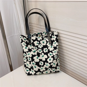 Detail of vintage floral tote bag with black leather straps and gold rivet accents