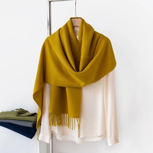 Dettaglio di sciarpa giallo senape effetto cashmere con frange su una gruccia elegante