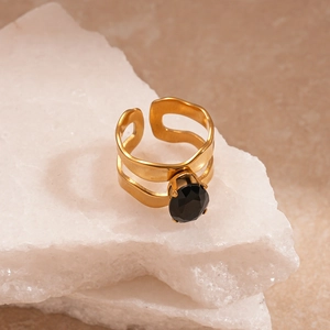 Détail d'une bague double dorée avec pierre noire ovale posée sur une pierre blanche