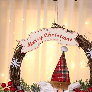Close-up of Merry Christmas sign on rustic twig wreath with red berries and snowman hat