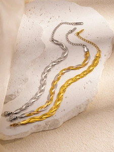 Detail of woven snake chain bracelets in gold, silver and two-tone steel on stone