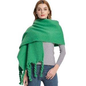 Close-up of green checkered mohair-like scarf with thick tassels worn by a model