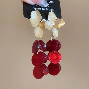 Detail of vintage gold flower stud earrings with three rows of red resin tassel pendants