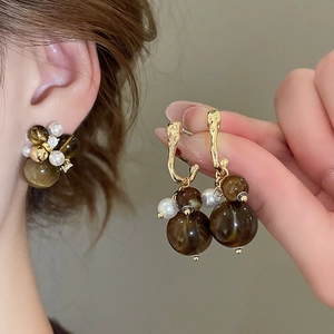 Detail of vintage earrings with amber resin beads, pearls and gold metal accents