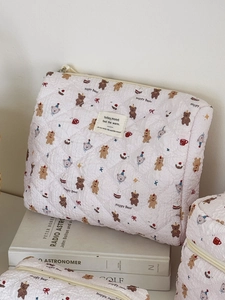 Détail de la texture d'une trousse matelassée blanche avec motifs d'ours et étiquette