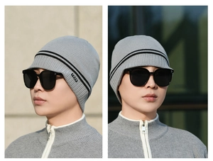 Detailed close-up of grey knit beanie with double black stripes and FBOE brand woven label