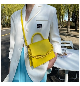 Outdoor lifestyle view of bright yellow leather crossbody bag with decorative chain link