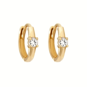 Close-up of gold huggie earrings with a sparkling round zircon in a four-prong setting
