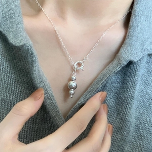 Detail of silver bead pendant necklace with three polished spheres on a fine chain