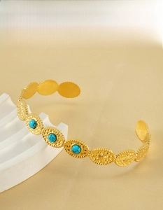 Gros plan détaillé du jonc plaqué or 18 carats avec pierres turquoise sur support blanc