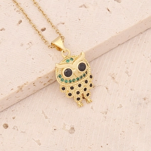 Detail of owl pendant with green and black crystals on an 18K gold-plated necklace