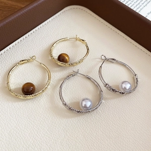Macro detail of twisted gold and silver hoop earrings with pearl and gemstone beads