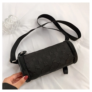 Detail of black cylindrical crossbody bag with checkered texture and wide strap