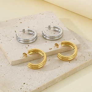 Minimalist gold and silver two-tone C-shaped layered metal hoop earrings on stone stand