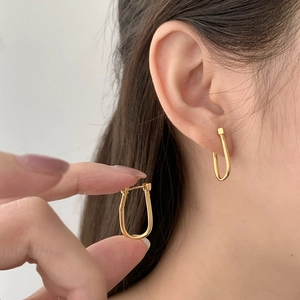 Macro detail of minimalist gold U-shaped hoop earrings showing smooth polished texture